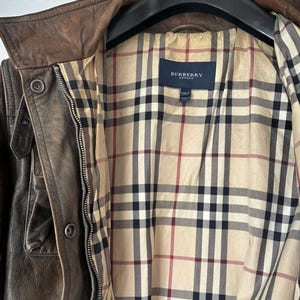 Giacca in pelle marrone dal design classico. L'etichetta Burberry è visibile all'interno della giacca.