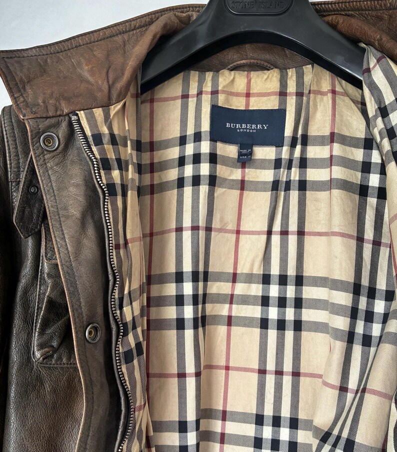 Giacca in pelle marrone dal design classico. L'etichetta Burberry è visibile all'interno della giacca.