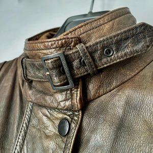Primo piano del colletto con chiusura a fibbia in metallo scuro con il marchio "Burberry" visibile.