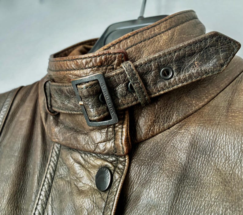 Primo piano del colletto con chiusura a fibbia in metallo scuro con il marchio "Burberry" visibile.
