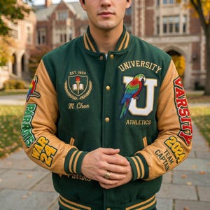 Op de afbeelding: Een donkergroen varsity jack met beige mouwen, voorzien van een grote witte letter U met een papegaai, de tekst University Athletics, een embleem met een fakkel en boek, de naam M. Chen, en mouwpatches met Parrots, War 24 en 2024 Team Captain.