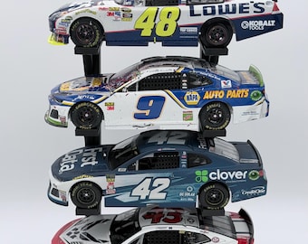 May include: A vertical display of four die-cast stock car models. The top car is blue and white with number 48 and Lowe's branding. Below it is a blue and white car with number 9 and NAPA Auto Parts. The third is blue with number 42 and Clover branding. The bottom car is red, white, and blue with number 43 and U.S. Air Force logos.