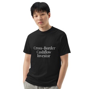 May include: Black t-shirt with the text "Cross-Border Cashflow Investor" in white. The shirt is a crew neck style and appears to be made of a soft material. The person in the image is wearing the shirt.