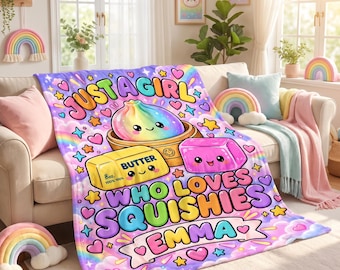 May include: A soft throw blanket featuring a colorful rainbow dumpling, a yellow stick of butter labeled 8oz, and a pink square block. The text reads JUST A GIRL WHO LOVES SQUISHIES EMMA. The background is a pastel sky with rainbows, stars, and hearts.
