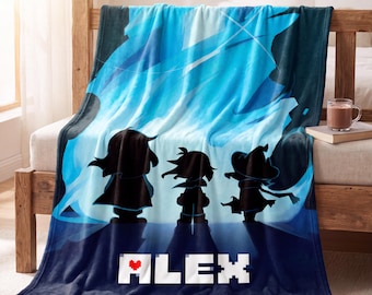 May include: A soft fleece blanket featuring a blue and dark blue gradient background with a bright light effect. Three black character silhouettes stand in the center. Below them, the name ALEX is printed in white block letters with a red heart.