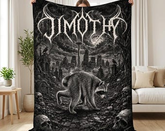 May include: A black and white throw blanket featuring a central raccoon walking through a graveyard with skulls and tombstones. In the background, a city skyline with the Space Needle is visible under a full moon. The text "JIMOTHY" is at the top.