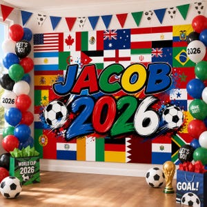 May include: A soccer-themed party backdrop featuring a collage of international flags, the name JACOB, and the year 2026 in bold, colorful lettering. Two soccer balls are integrated into the design, flanked by balloon arches and gift bags.