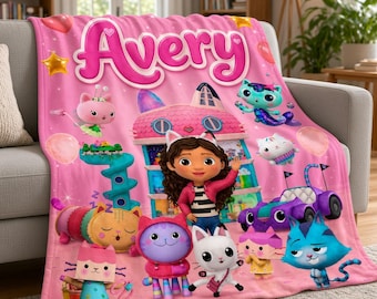May include: A pink fleece blanket featuring the name Avery in large pink letters at the top. The design includes various cartoon cat characters, a multi-story dollhouse, a purple toy car, and colorful balloons against a starry background.