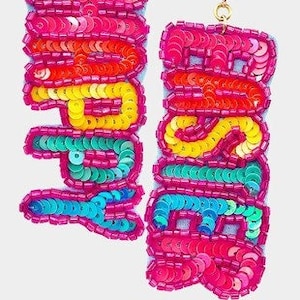 May include: Bright pink sequin earrings with the word "JOY" spelled out in colorful sequins. The letters are outlined in a contrasting color, with a clear gem at the top of each earring.