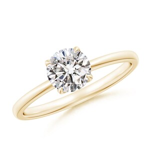 May include: A solitaire engagement ring with a round-cut diamond set in a yellow gold band. The diamond is the focal point, sparkling brightly against the smooth, polished gold. The ring's design is simple and elegant.
