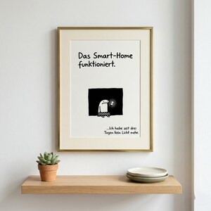 May include: A framed wall art print featuring a cartoon character in a dark room holding a glowing smartphone. The text reads: Das Smart-Home funktioniert. ...Ich habe seit drei Tagen kein Licht mehr. The frame is gold and the print is white.