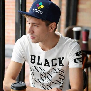 Könnte beinhalten: Eine marineblaue Baseballkappe mit einem farbenfrohen Logo. Die Person trägt ein weißes T-Shirt mit dem Aufdruck "BLACK". Das Bild enthält auch den Text "Custom Printed Caps".