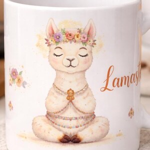 Op de afbeelding: Witte keramische mok met een mediterende lama met een bloemenkrans en een kralenketting. Op de mok staat het woord "Lamas" in een oranje lettertype. De mok staat op een neutrale onderzetter.