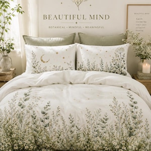 May include: A white duvet cover and two matching pillowcases featuring a green botanical print of wildflowers and foliage. The bedding set includes gold celestial accents like a crescent moon and stars, with the text BEAUTIFUL MIND printed above.