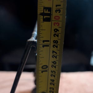 May include: A close-up of a metal object with a yellow measuring tape. The tape shows a measurement of approximately 10 inches. The object appears to be a decorative piece or part of a larger structure.