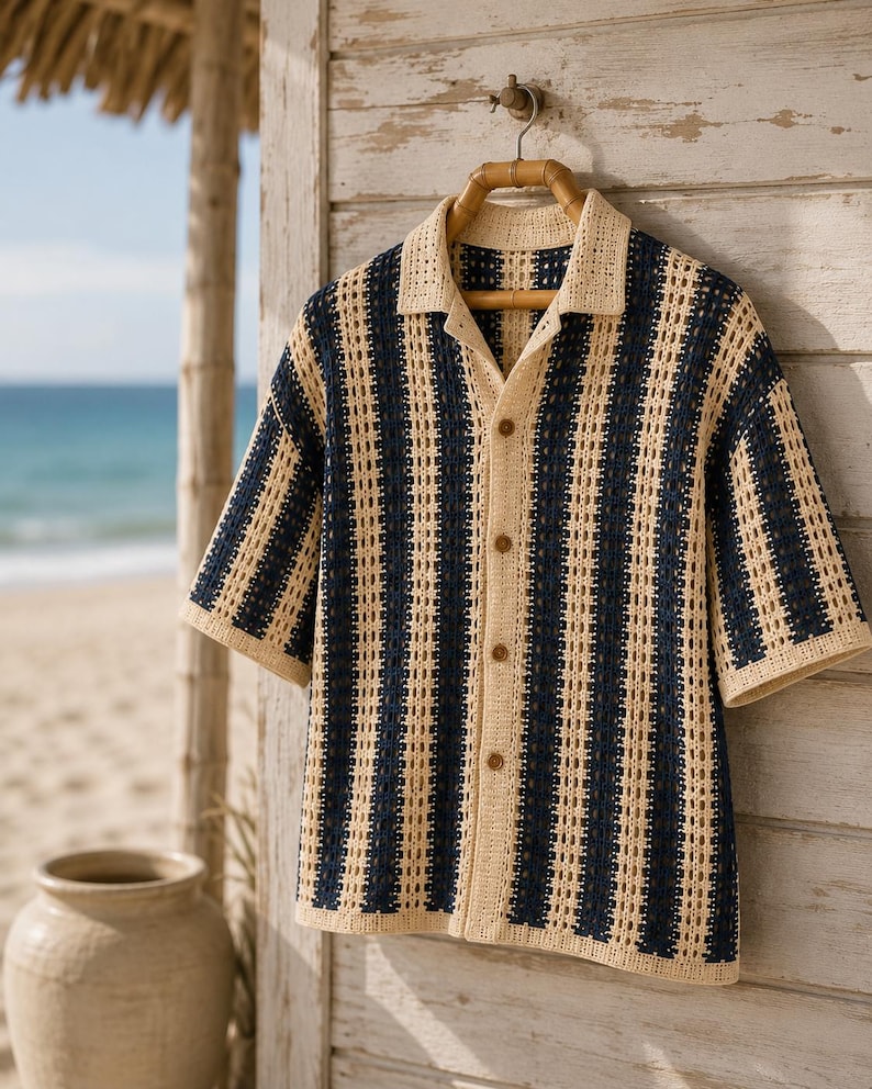 May include: A short-sleeved button-down shirt featuring a vertical striped pattern in cream and navy blue. The garment is crafted from a crochet knit fabric with an open-work texture, a classic collar, and four brown buttons down the front center.