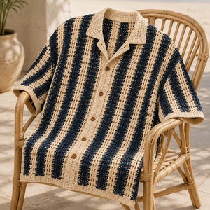May include: A short-sleeved button-down shirt featuring a vertical striped pattern in navy blue and cream. The garment is crafted with an open-knit crochet texture, a classic collar, and five brown buttons running down the center front placket.