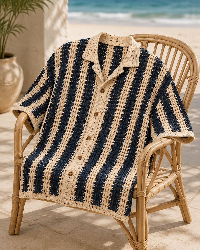 May include: A short-sleeved button-down shirt featuring a vertical striped pattern in navy blue and cream. The garment is crafted with an open-knit crochet texture, a classic collar, and five brown buttons running down the center front placket.