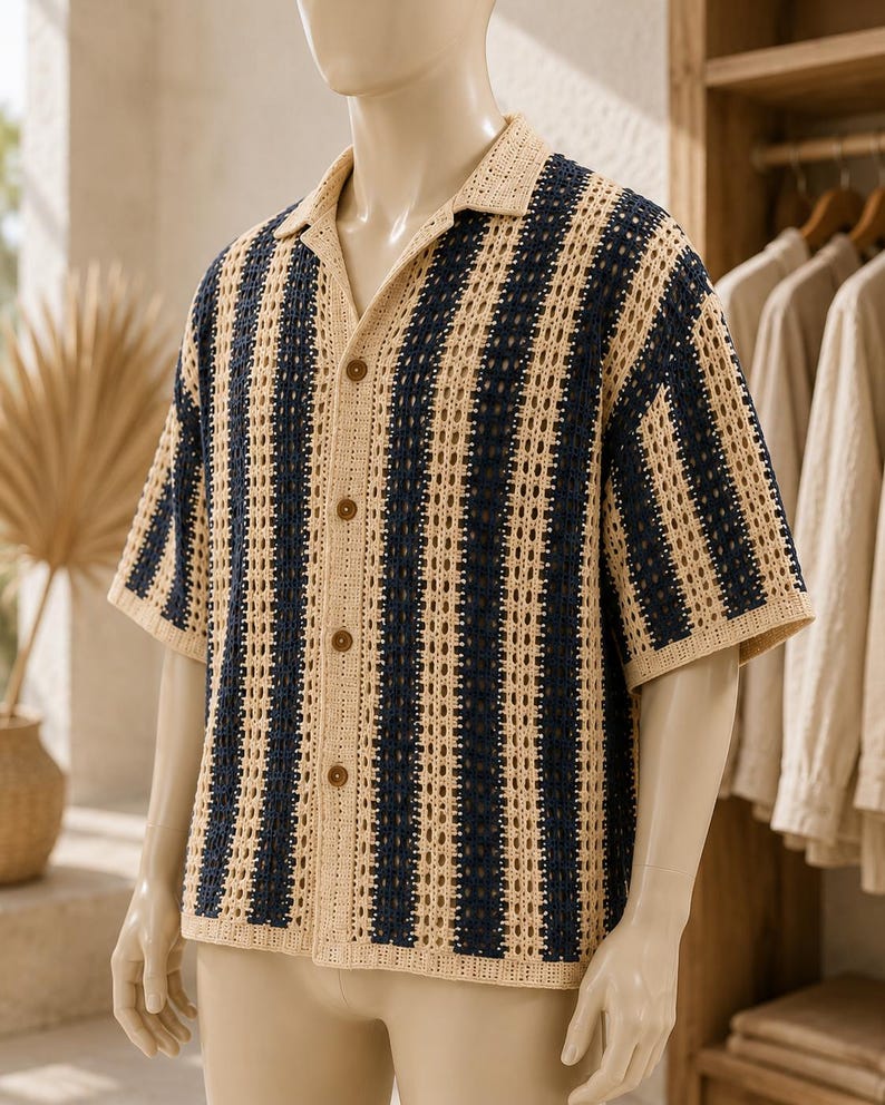 May include: A short-sleeved button-down shirt featuring a vertical striped pattern in navy blue and beige. The garment is constructed with an open-knit crochet texture, a classic collar, and four brown buttons down the center front placket.