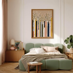 Cozy art print of stacked books and airy white flowers on a tan background, centered above a green upholstered bed with matching nightstands.