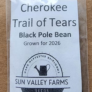 May include: A clear plastic bag containing seeds. The bag has a white label with the text "Cherokee Trail of Tears Black Pole Bean Grown for 2026". The label also includes the text "Sun Valley Farms Seeds Woodbury, TN".