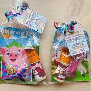 May include: Two cellophane gift bags, each containing a coloring book, pencils, candy, and a tag that reads "THANKS FOR MAKING MY BIRTHDAY JUST WRITE" and "LOVE, SIERRA". One bag features a pig, the other a sheep.