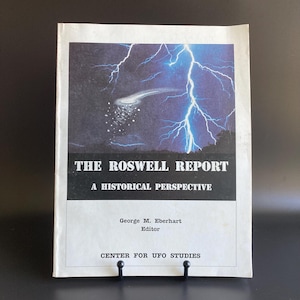 May include: The Roswell Report: A Historical Perspective book. The cover features a dark blue sky with a lightning bolt and a white object. The title is in bold white letters, with the author and publisher information below.