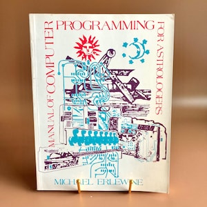 May include: A vintage book titled "Programming for Astrologers" with a white cover. The cover features a red sun and a turquoise crescent moon design, along with a complex illustration in turquoise and purple. The author's name, Michael Erlewine, is at the bottom.