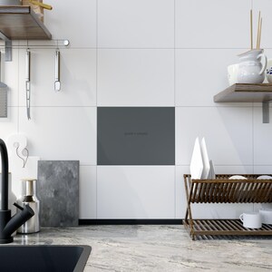 May include: A modern kitchen scene with white tiled walls and a gray accent panel. A wooden dish rack holds white plates and mugs. Kitchen utensils hang from a metal rack. The text "quiet x empty" is visible on the gray panel.