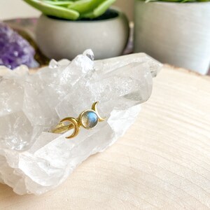 May include: Gold ring with a blue labradorite gemstone and three crescent moon designs.
