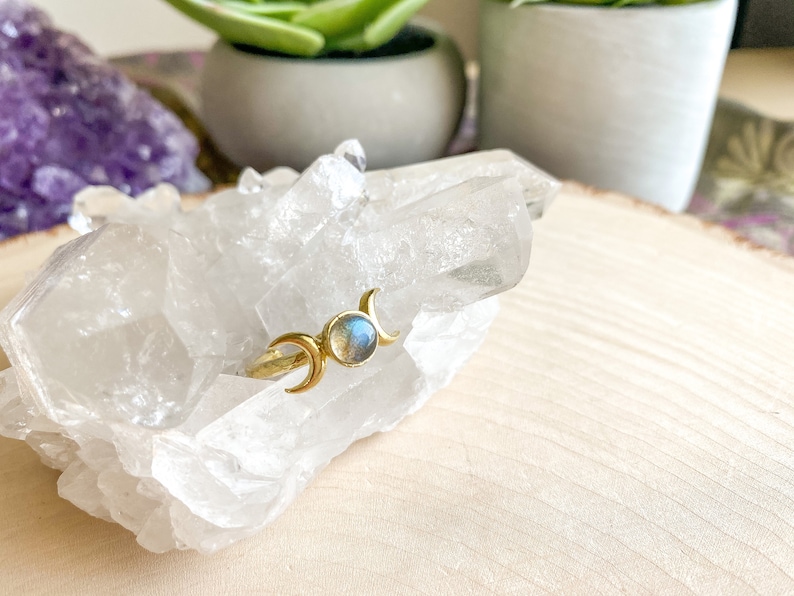 May include: Gold ring with a blue labradorite gemstone and three crescent moon designs.