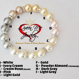 May include: A pearl bracelet with a colour gradient, from white to light grey, with shades of cream, pink, and gold. Rhinestone spacers separate the pearls. The bracelet is from Queen Me Jewelry.