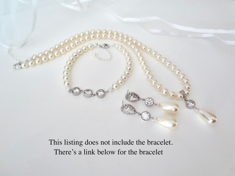 May include: A pearl necklace, bracelet, and earrings set. The necklace and bracelet are made of round pearls. The earrings have a teardrop pearl and a round, clear stone. The text on the image says, "This listing does not include the bracelet."
