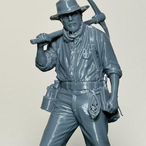 May include: A gray figurine of a miner wearing a hat, work shirt, and pants, carrying a pickaxe over his shoulder. The miner has a tool belt with pouches and a rope hanging from it. The figurine is detailed and realistic.
