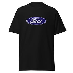 May include: Black t-shirt with a blue and white oval logo that reads "Fuct". The logo is centered on the front of the shirt. The shirt has short sleeves and a crew neck.