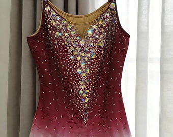 May include: A sleeveless leotard featuring a deep burgundy to white ombre gradient. The bodice is heavily embellished with iridescent crystals in a central vertical pattern, with smaller scattered crystals throughout and a jagged white hemline.