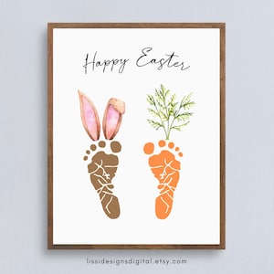 May include: A framed print with the words "Happy Easter" in script. The artwork features brown and orange footprints, forming a bunny and a carrot. Bunny ears and carrot tops are added to the footprints. The Etsy shop URL is at the bottom.
