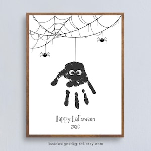 Può includere: Una stampa incorniciata con un'impronta di mano nera trasformata in un ragno con due occhi bianchi, appesa a un'illustrazione di ragnatela nera. Il testo "Happy Halloween 2026" è stampato sotto, con un piccolo URL in basso.