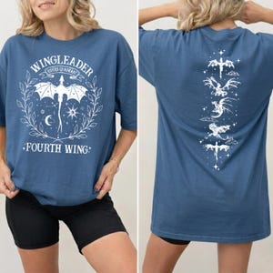 A woman wearing a blue t-shirt with a graphic design featuring a dragon and the text "WINGLEADER" and "FOURTH WING".