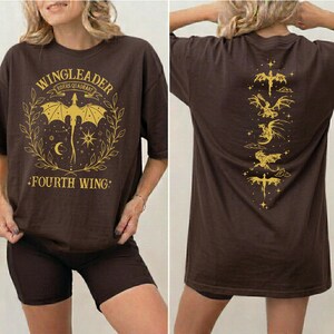 a woman wearing a brown t-shirt with a graphic design on the front and back.