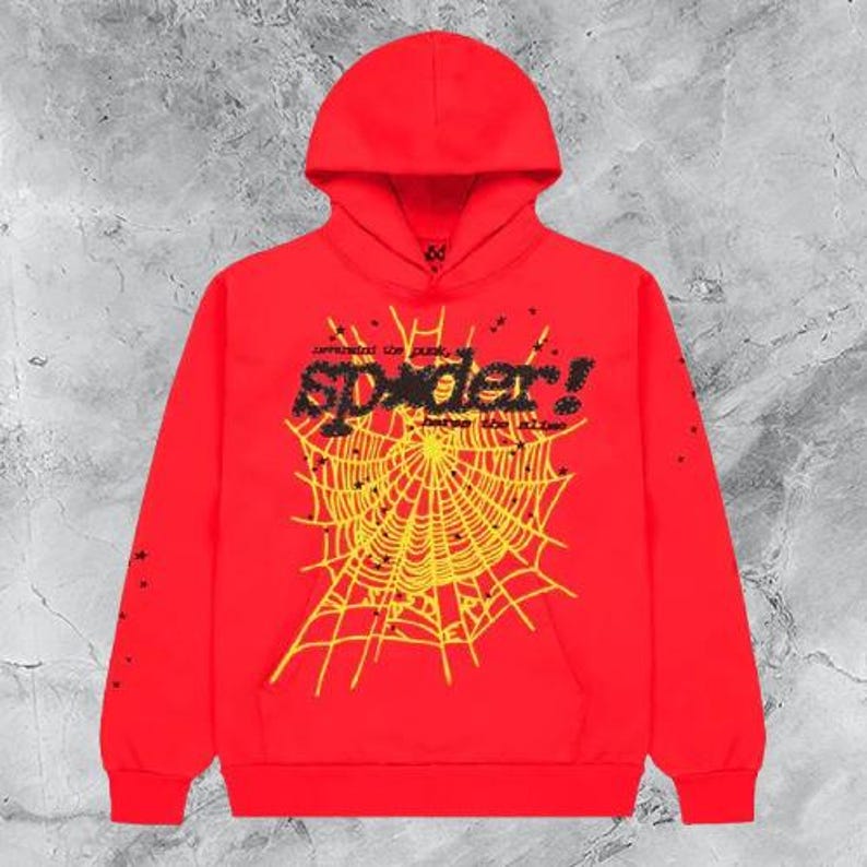 Op de afbeelding: Een rode hoodie met een geel spinnenwebontwerp en het woord "spider!" in zwart en geel. De hoodie met lange mouwen heeft kleine zwarte sterren.