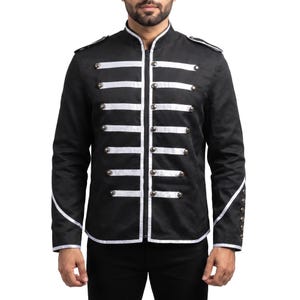 May include: A black military-style jacket featuring a high collar, a central zipper closure, and white horizontal trim across the chest. The garment includes shoulder epaulets, metallic buttons along the front and cuffs, and white piping details on the sleeves.