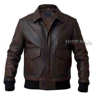 Könnte beinhalten: Braune Lederjacke im klassischen Bomberstil. Sie hat einen Kragen, zwei Vordertaschen und einen gerippten Strickbund und -bündchen. Die Jacke hat ein Used-Finish. Der Markenname "HIDENZA" ist auf der rechten Seite sichtbar.