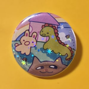 May include: A round button with a whimsical illustration. The design features a light brown bunny, a green dinosaur, and a brown cat, set against a backdrop of a house, rainbow, and stars. The button has a holographic, glittery effect.
