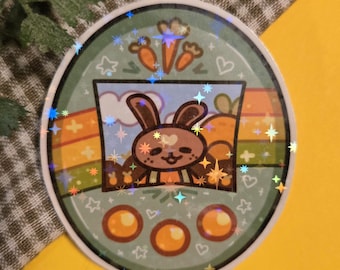 May include: A round sticker featuring a cartoon bunny inside a window with carrots and a rainbow. The sticker has a holographic effect with stars and sparkles. The bunny is brown with a white heart on its face. The sticker has three orange circles at the bottom.
