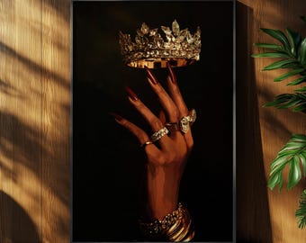 May include: A framed artwork featuring a hand adorned with gold jewelry, holding a gold crown with clear gemstones. The hand has long red nails and is set against a dark background. A gold bracelet is on the wrist.