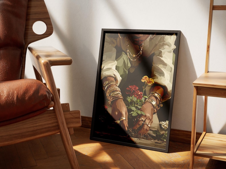 May include: A framed art print depicts a person tending to flowers. The person is wearing gold jewelry and a light-colored shirt. The flowers are red and yellow. The frame is black.