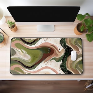 May include: A rectangular mouse pad with a black border features an abstract design in shades of olive green, brown, cream, and black. The pattern resembles flowing paint or marbled textures. A white computer mouse rests on the pad.