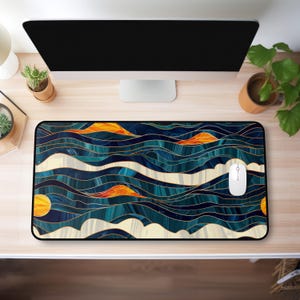 May include: A rectangular mousepad with a colorful abstract design. The pattern features wavy lines in shades of blue, teal, orange, and cream, outlined with gold. A white computer mouse sits on the pad.