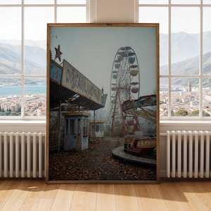 May include: A framed print of an abandoned amusement park. The image features a Ferris wheel, carousel, and the sign "DREAMLAND PARK". The scene is overcast with a muted color palette, and the structures show signs of age and disrepair.